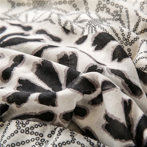 Close-up detail of lightweight cotton-linen scarf fabric with black dot floral patterns