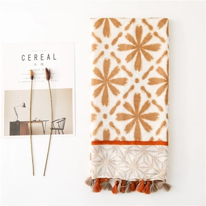 Detail of floral printed scarf with orange tassels and bohemian geometric patterns