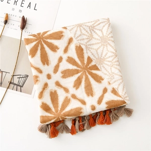 Detail of floral and geometric pattern scarf with orange tassels and cotton linen texture
