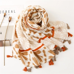Detail of artistic cotton scarf featuring warm brown patterns and colorful tassels