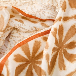 Close-up of cotton linen scarf showing brown floral prints and orange stitched edges