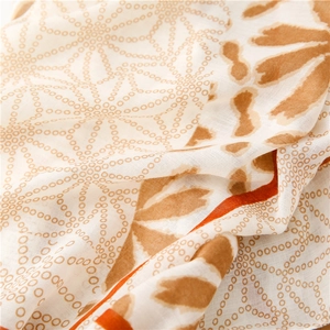 Macro detail of breathable linen-feel scarf fabric with brown polka dots and orange trim