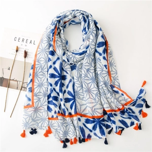 Blue floral and polka dot cotton linen scarf with orange tassels on white background