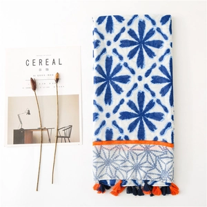 Detail of white cotton scarf with blue floral prints and orange fringe tassels