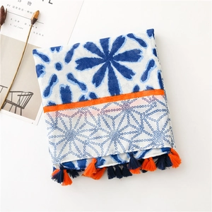 Detail of floral geometric cotton scarf with orange stripes and colorful tassel trim