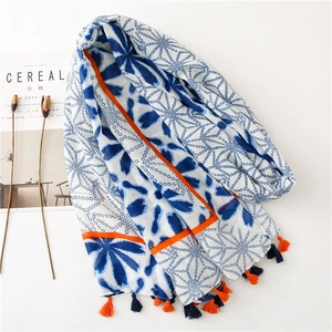 Detail of floral printed cotton scarf with vibrant leaves patterns and bicolor fringe