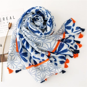 Detail of white cotton linen scarf featuring blue floral dots and colorful tassels