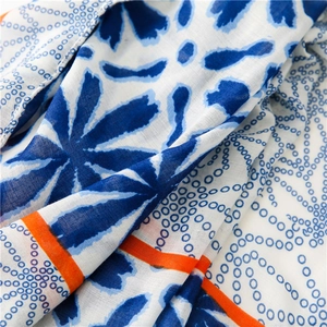 Detail of soft linen-feel scarf showing blue floral prints and orange accent lines