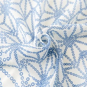 Macro detail of blue floral print on white cotton-linen fabric with soft draped texture