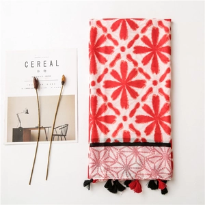Detail of bohemian scarf with red floral prints, geometric patterns and tassels