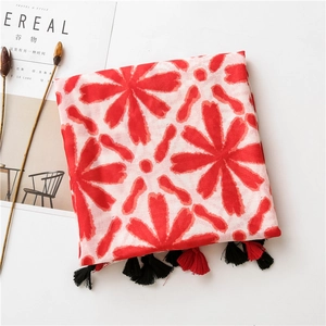 Detail of floral linen shawl with red blossoms and black red tassel edges on white background