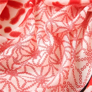 Macro detail of breathable fabric with red dot pattern on soft pink floral scarf