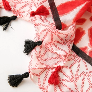 Detail of white cotton scarf with red circular patterns and red black tassel fringe