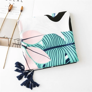 Detail of tropical leaf print beach scarf with dark blue fringe tassels and soft texture