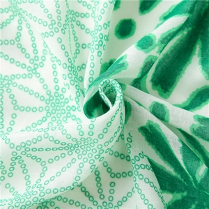 Detailed close-up of soft cotton-linen fabric with green polka dots and floral print patterns