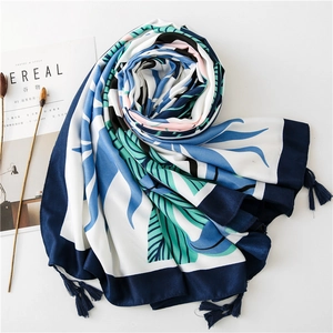 Detail of tropical leaf print shawl with navy blue border and tassel decorations
