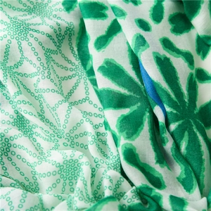 Close-up of lightweight floral scarf showing green flower patterns and cotton texture