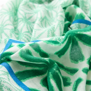 Close-up of lightweight green and white scarf with floral dots and woven texture