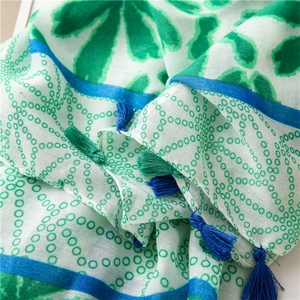 Detailed view of lightweight floral scarf fabric with vibrant green tassels and pattern