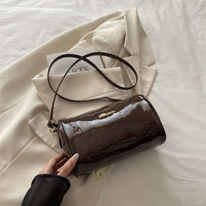 Glossy coffee cylindrical bucket bag with gold metal FASHION lettering on white blazer