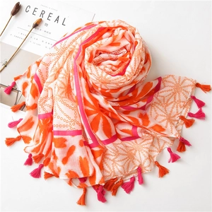 Detail of vibrant floral dot scarf featuring pink and orange tassels on a white setup