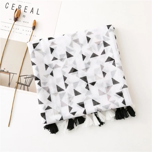 Detailed view of geometric triangle pattern and cotton tassels on a soft white scarf