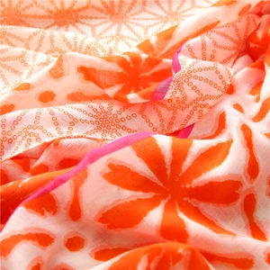 Close-up of lightweight floral scarf showing vibrant orange and pink print and fine texture