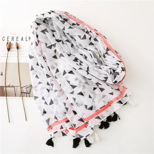 Detail of a lightweight white scarf with black triangles, orange stripes, and tassels