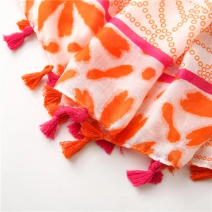 Detailed macro of orange and fuchsia floral scarf featuring double-colored fringe tassels