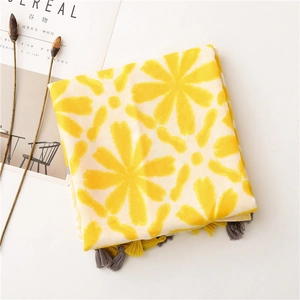 Detail of yellow cotton-linen scarf with large floral patterns and tassels