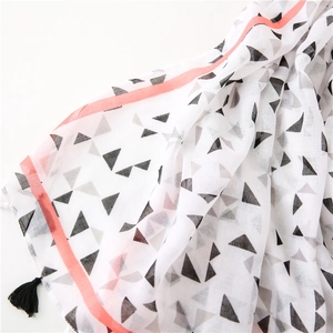 Detail of soft scarf with geometric prints and tassels focusing on fabric texture