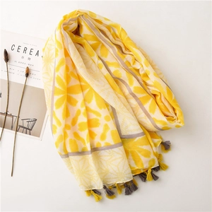 Detail of floral pattern scarf with yellow and grey tassels on a minimalist background