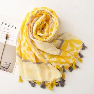 Flat lay of yellow geometric floral scarf with long tassels beside CEREAL magazine