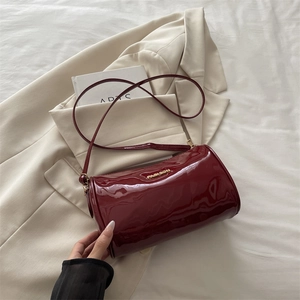 Chic burgundy patent leather cylinder shoulder bag with golden Fashion logo and strap