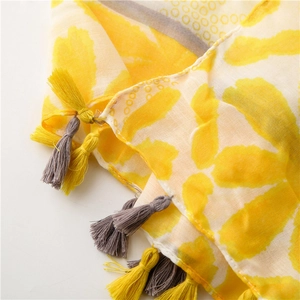 Detail of yellow and gray scarf featuring delicate fringe tassels and abstract print pattern