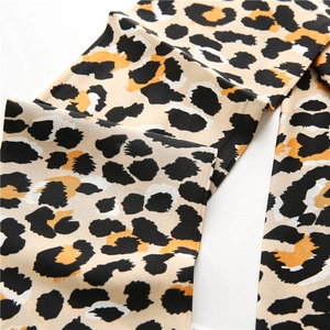 Détail du tissu foulard en soie léopard montrant la texture douce et le drapé élégant