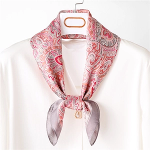 Close-up of paisley silk scarf on white shirt with a decorative pearl pendant buckle