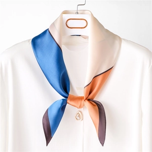 Silk neck scarf with geometric color block patterns tied on a white collared shirt