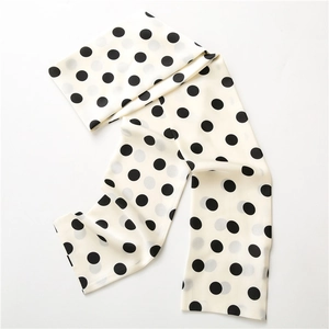 Detailed view of lightweight satin scarf featuring classic black polka dots on cream white