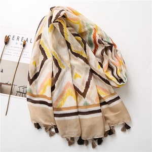 Detail of colorful geometric pattern scarf with bohemian tassels on white background
