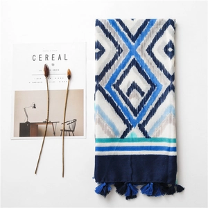 Detail of bohemian cotton linen scarf featuring blue geometric patterns and fringed edges