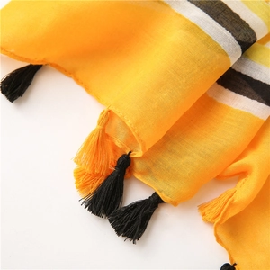 Close-up of yellow and black striped cotton linen shawl with braided tassels