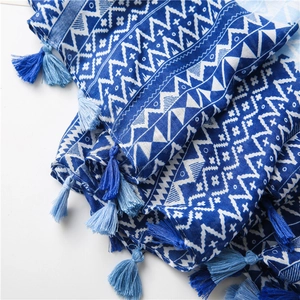 Detailed close-up of blue geometric pattern linen shawl with handmade fringe tassels