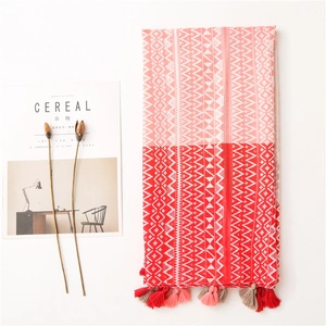 Detail view of woven geometric scarf with red and pink gradient pattern and tassels