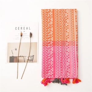 Detail of geometric pattern cotton shawl with colorful tassels and gradient orange hue