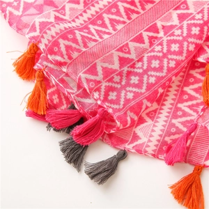Detail of rose pink scarf with geometric patterns and vibrant multicolor tassels