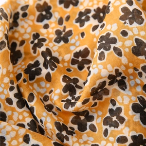 Détail d'une écharpe légère en voile avec motif floral jaune et texture de tissu macro