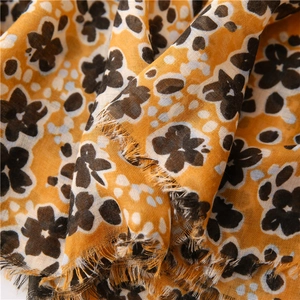 Détail d'une écharpe fleurie jaune en coton montrant la texture et les bords à franges