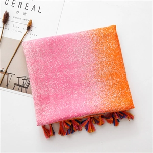 Detail of pink and orange gradient scarf with snowflake texture and colorful tassels