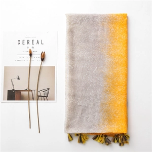Detail of grey and yellow gradient scarf with fine tassels next to a magazine